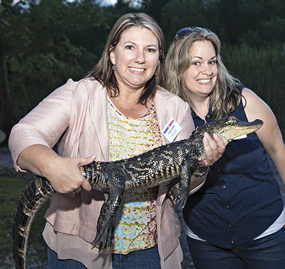 Attendees pose with a friendly gator at a swamp party also known as a "Cajun Fais Do Do." Credit Riverview Photography, Linda Reineke