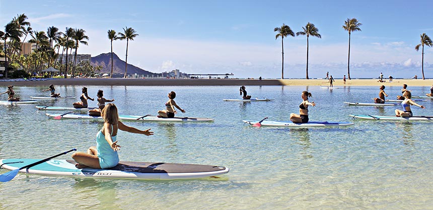 Group yoga on standup paddleboards at Hilton Hawaiian Village Waikiki Beach Resort.