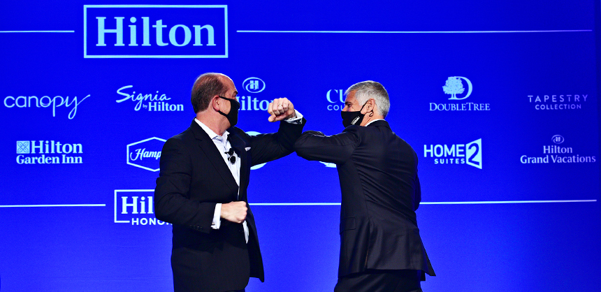 Passanante, left, and Chris Nassetta, Hilton president & CEO, right, greet each other with an elbow bump at a customer event.